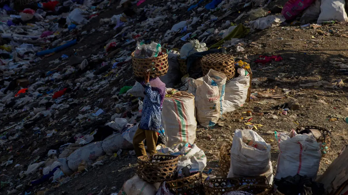 PEJUANG RUPIAH: Seorang pemulung menjunjung keranjang berisi barang bekas hasil pilahan di antara tumpukan sampah TPAR Kebon Kongok, Lombok Barat, beberapa waktu lalu. (IVAN/LOMBOK POST)