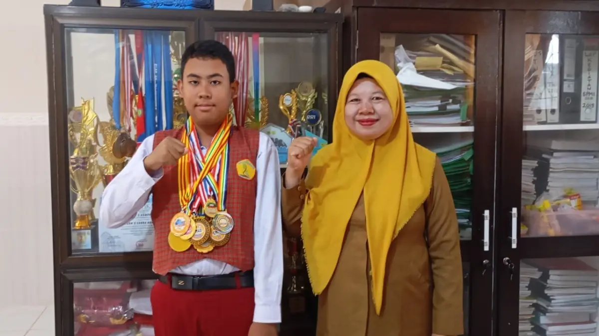 MEMBANGGAKAN: Tristan Naufal Ardhani, murid SDN 13 Mataram yang meraih puluhan medali dalam berbagai lomba sains bersama kepala sekolah di sekolah setempat, Selasa (1/9).