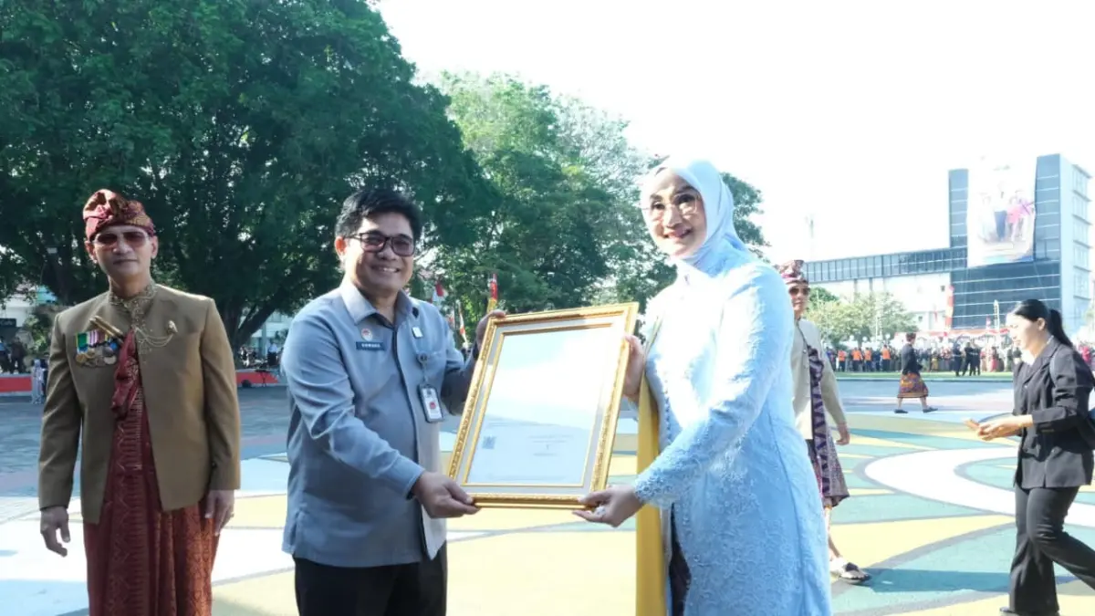 Kepala Divisi Peraturan Perundang-undangan dan Pembinaan Hukum Kanwil Kemenkum NTB Edward James Sinaga menyerahkan Sertifikat Kekayaan Intelektual Bros Tembolak kepada Noviani Danar Kinnastri dalam rangkaian HUT ke-33 Kota Mataram di Lapangan Sangkareang, Senin (31/8/2026).