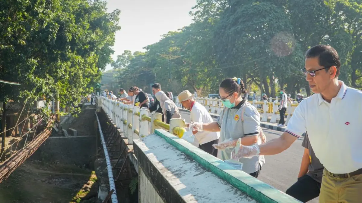 Pejabat dan pegawai kota bekerja gotong royong mengecat kanstin trotoar.