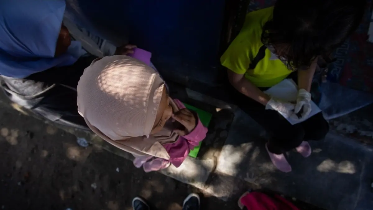 Petugas kesehatan dari Posyandu sedang mendampingi seorang anak saat proses skrining tumbuh kembang anak. 

