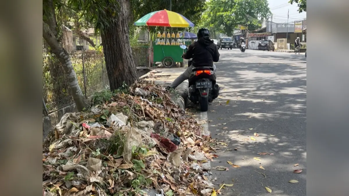 Seorang pengendara berhenti di dekat tumpukan sampah saluran jalan Adi Sucipto.