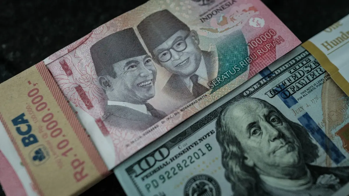Uang pecahan Rp100.000 ditampilkan berdampingan dengan uang pecahan 100 dolar AS di sebuah tempat penukaran valuta asing di Jakarta, 4 Juni 2026, setelah nilai tukar rupiah melemah menembus Rp18.000 per dolar AS untuk pertama kalinya. (Foto: Yasuyoshi Chiba/AFP)