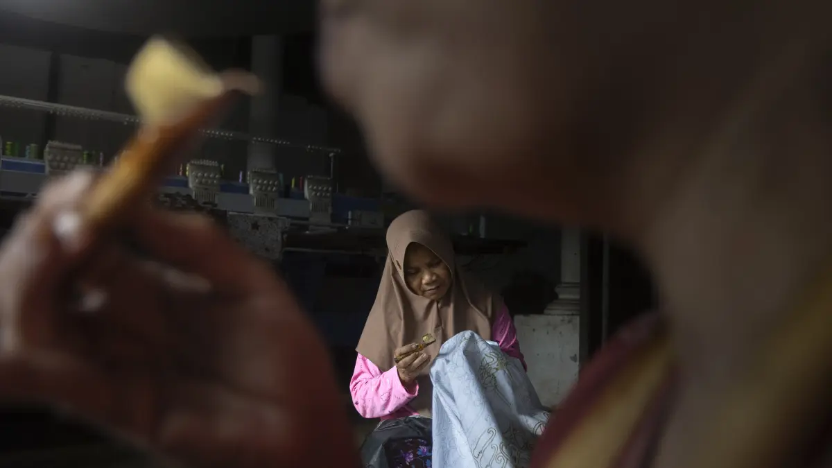 Ketelitian Canting: Seorang perajin fokus menggoreskan lilin malam pada lembaran kain di Sanggar Batik Temas, Kota Batu. Ketekunan tangan perajin ini menjadi fondasi utama kelestarian batik tulis tradisional di tengah persaingan industri kain cetak (19/17/2026).