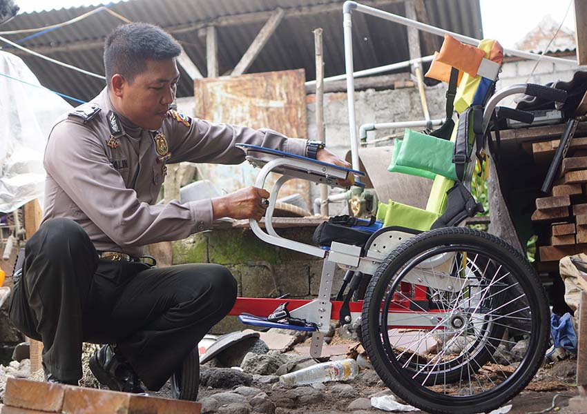 MENYIAPKAN KURSI RODA: Brigadir Agus Salim sedang menyiapkan kursi roda baru untuk anak lumpuh dari keluarga tak mampu di Desa Sukamulia, Kecamatan Sukamulia, belum lama ini.