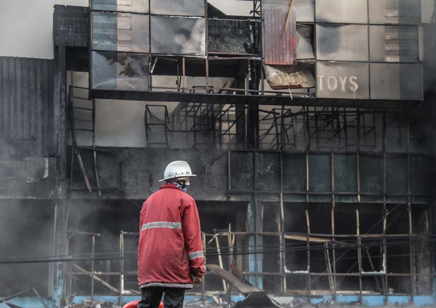 KEMBALI MENYALA: Pihak kepolisian memadamkan percikan api yang muncul kembali di toko mainan dan petasan di Jalan Selaparang, Cakranegara, kemarin (3/1).