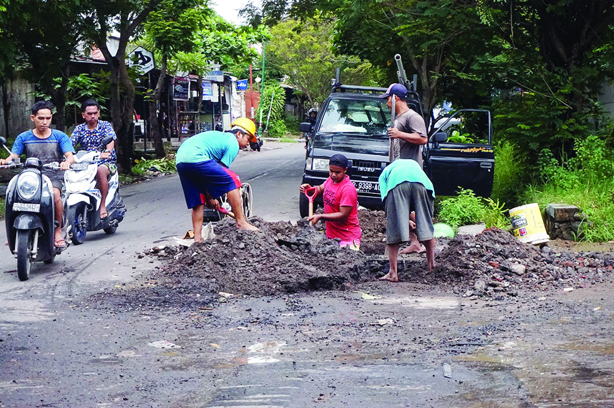 GALI PIPA BOCOR: Empat orang pekerja lapangan PDAM Giri Menang menggali aspal di Jalan Tumpang Sari Cakranegara guna memperbaiki pipa air yang bocor beberapa waktu lalu.