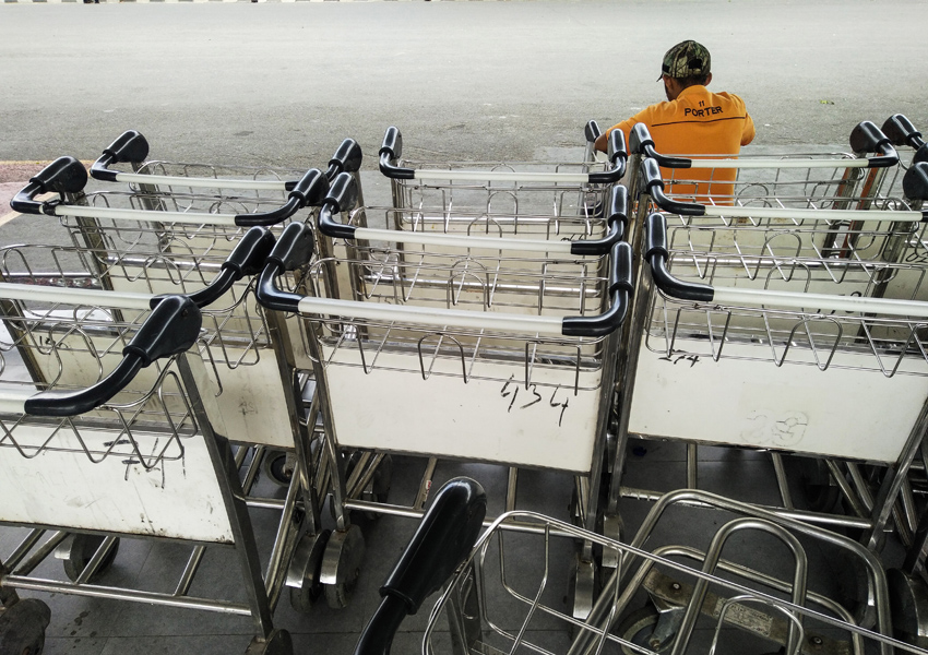 NGANGGUR: Seorang porter duduk di depan tumpukan trolley pembawa barang di Bandara Internasional Lombok, Praya, Lombok Tengah, kemarin (15/2).