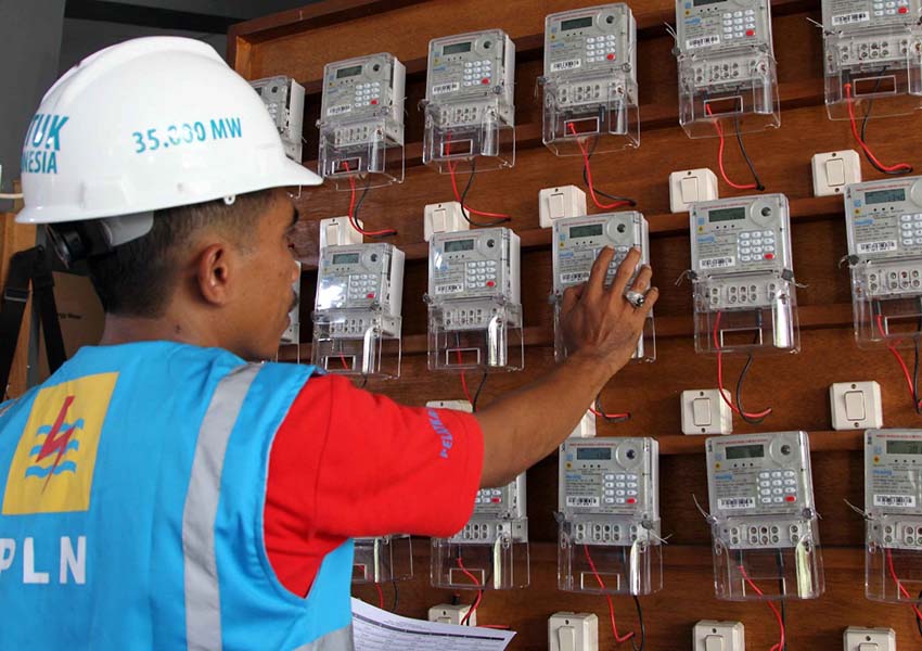 PEMASANGAN DAYA: Petugas PLN Wilayah NTB  menunjukkan kWh meter yang akan dipasang di rumah warga.