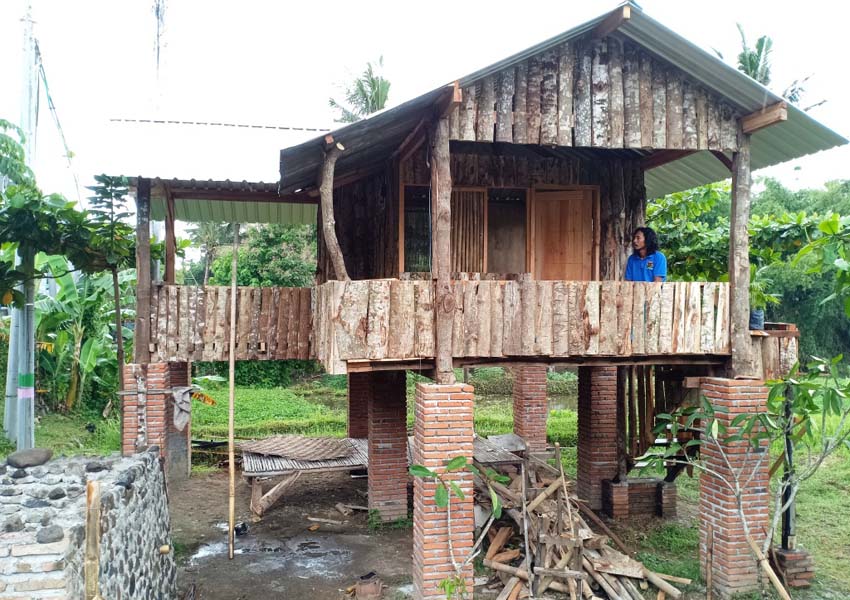 NIKMATI HIDUP: Kaderlan sedang duduk di teras rumah kayunya, sembari menikmati suasana siang yang gerimis di pinggir Jalan Ahmad Yani, Sayang-Sayang, kemarin (15/2).