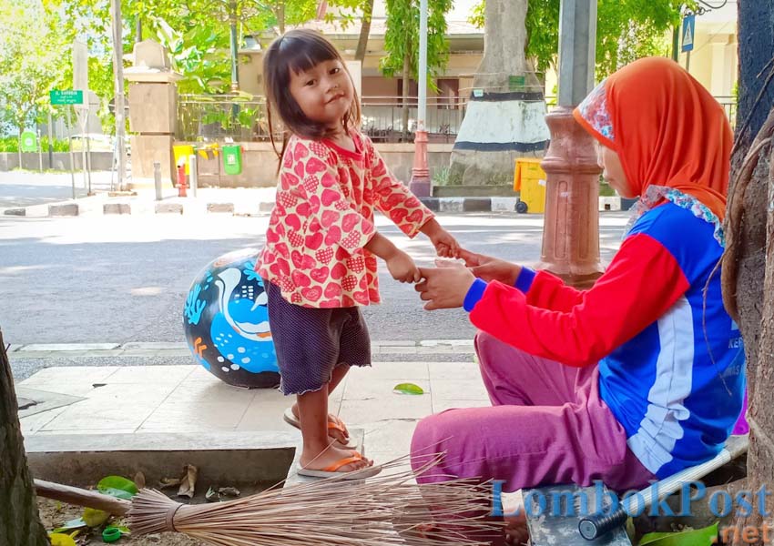 BAHAGIA DI MANA SAJA: Muslihatun bermain dengan putrinya di sela-sela istirahat siang menyapu jalanan kota, Senin (25/2).