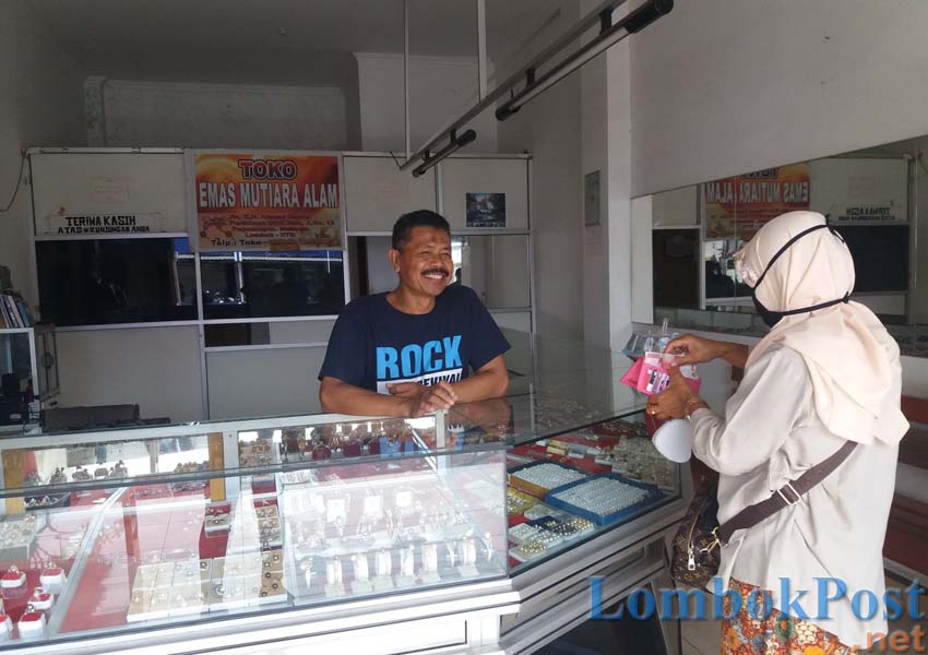 TERUS BERTAHAN: Salah satu pedagang mutiara Lombok Sahnan terlihat sibuk melayani seorang pembeli dilapak nya, kemarin (28/3).