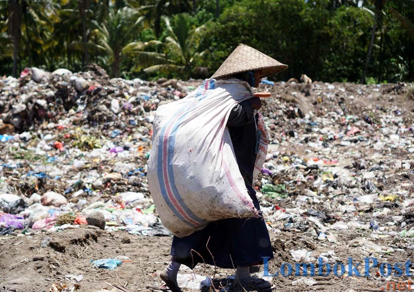 MENGAIS REZEKI: Seorang pemulung terlihat mengangkut sampah pilihan yang akan dijual pada pengepul di UPT TPA Ijobalit, Kecamatan Labuhan Haji, kemarin