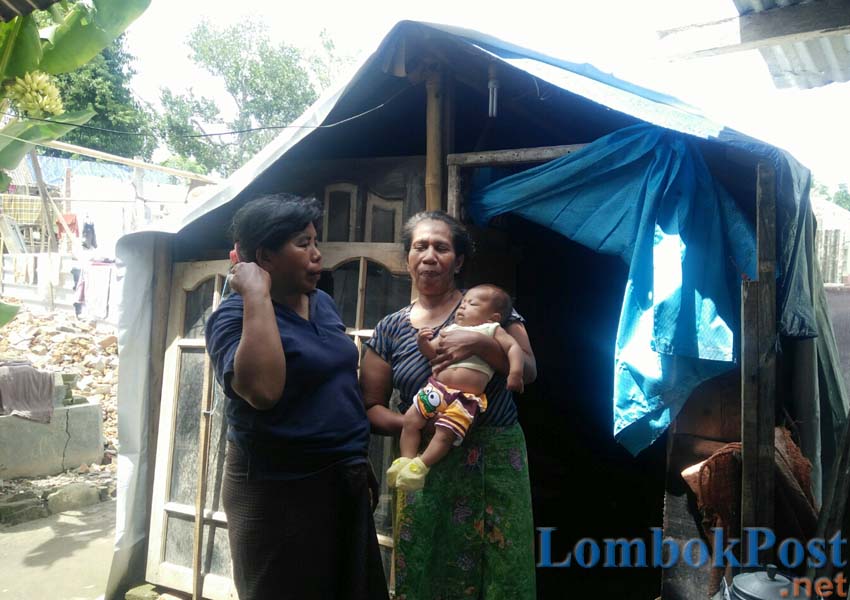 BERTAHAN DI TENDA: Sahnim, salah seorang warga korban gempa di Desa Dopang, Kecamatan Gunungsari saat menggendong cucunya pekan lalu.