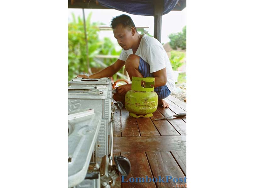 SELALU ADA AKAL: Amir tengah membuat kompor gas dari bekas kompor minyak tanah di rumahnya kawasan Selagalas, Kota Mataram, kemarin (25/3).