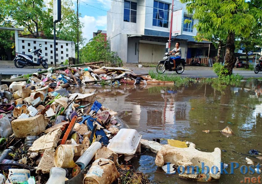 DUH KOTORNYA: Seorang pengendara melintas di dekat drainase Jalan Raden Panji Anom, Karang Buaya Pagutan Timur, Kota Mataram, Minggu (3/3). Drainase terlihat kotor karena dipenuhi sampah.