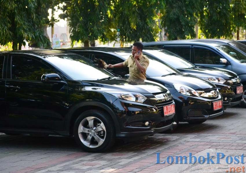RAWAT TERATUR: Seorang sopir sedang membersihkan kendaraan dinas dari debu dan kotoran yang lengket di body mobil, beberapa waktu lalu.