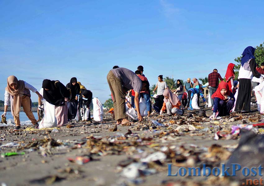 GOTONG ROYONG: Sejumlah pemuda yang tergabung dalam komunitas Plastik Bergerak sedang membersihkan sampah di pesisir pantai Labuhan Haji, kemarin