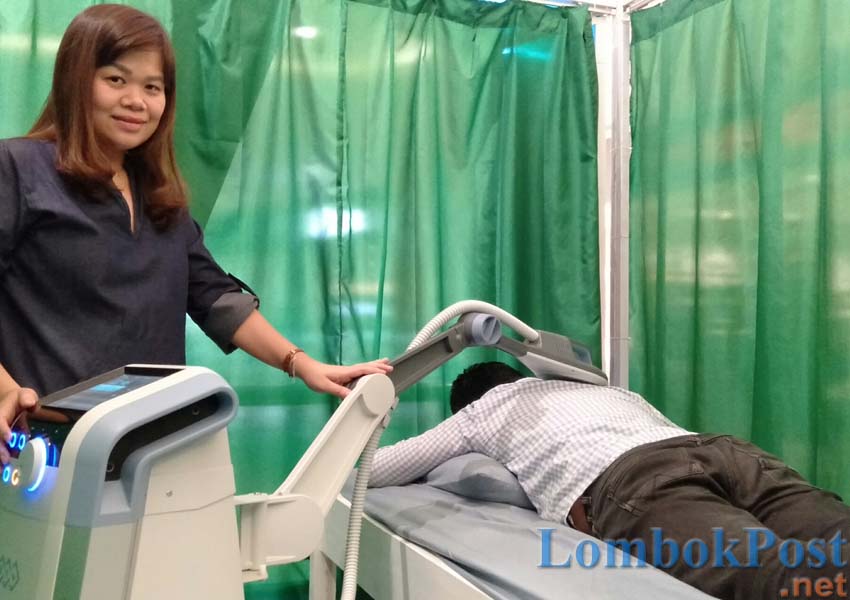 FREE TREATMENT: Spesialis Rehabilitasi Medik RSUD Kota Mataram dr Verra Sp KFR tengah memberikan treatment terapi Super Inductive System (SIS) pada salah satu pengunjung dalam booth pameran rehabilitasi medis RSUD Kota Mataram di LEM, Sabtu (30/3).