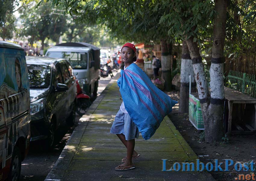 MENCARI REZEKI: Aji, seorang anak dari Kecamatan Selong sedang memulung di seputaran Hutan Selong, kemarin (2/5).