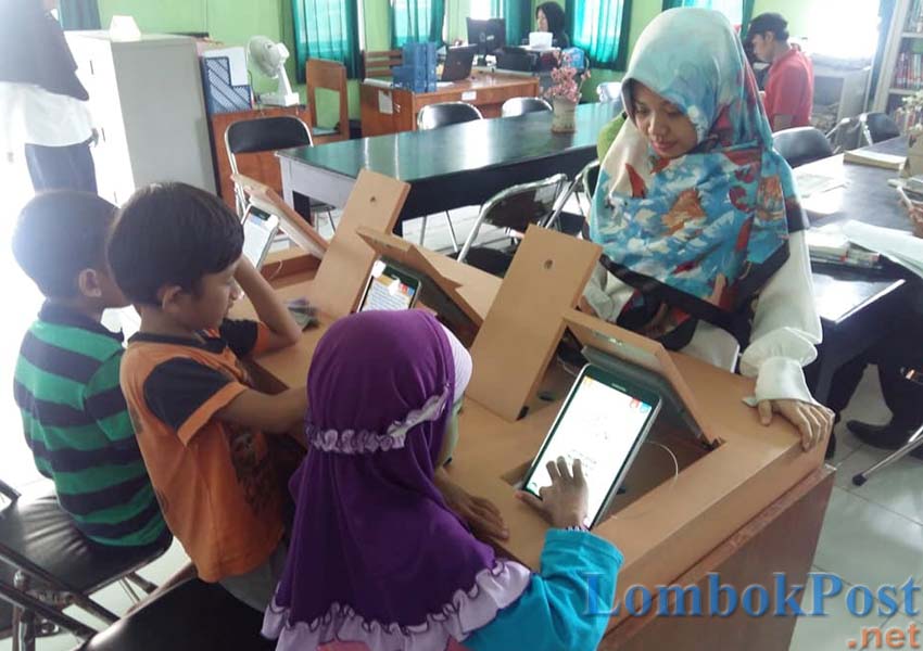 MEMBACA BUKU DIGITAL: Pengunjung perpustakaan sedang menikmati layanan buku digital dalam apilkasi iLotim di Kantor Dinas Perpustakaan dan Kearsipan Lotim, belum lama ini.