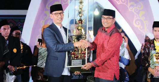 DAPAT JUARA: Wakil Wali Kota Mataram H Mohan Roliskana menyerahkan piala bergilir MTQ XVIII kepada Camat Mataram Zarkasyih, saat penutupan MTQ XVIII di Lapangan Karang Genteng, Selasa malam (23/7).