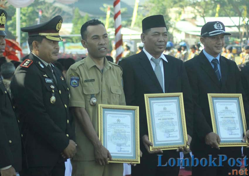 TERIMA PENGHARGAAN: Kepala Desa Taman Ayu Tajuddin saat menerima penghargaan dari Polda NTB saat upacara HUT Bhayangkara ke-73, kemarin