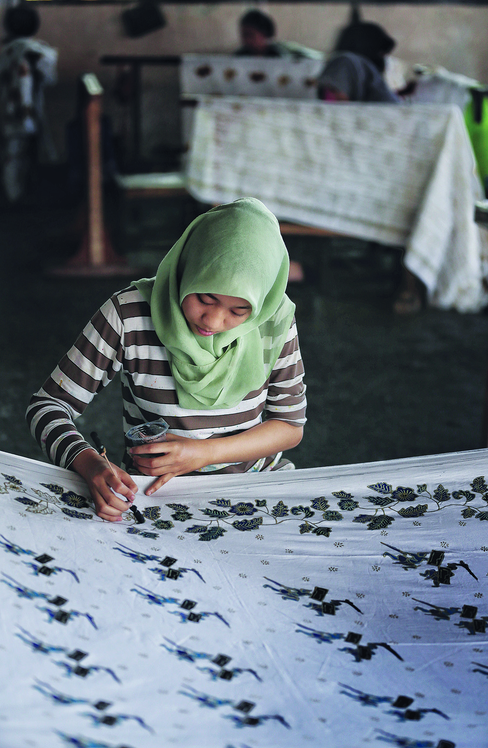 KHAS: Seorang wanita mewarnai motif gambar peresean pada batik sasambo di SMK 5 Mataram, kemarin (8/10). Motif peresean merupakan salah satu ciri khas batik ini.