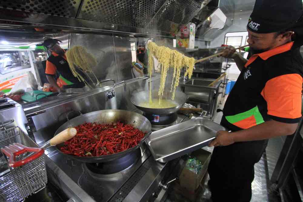 MOBIL: Salah seorang relawan memasak bagi korban bencana di Humanity Food Truck. (ACT For Lombok Post )