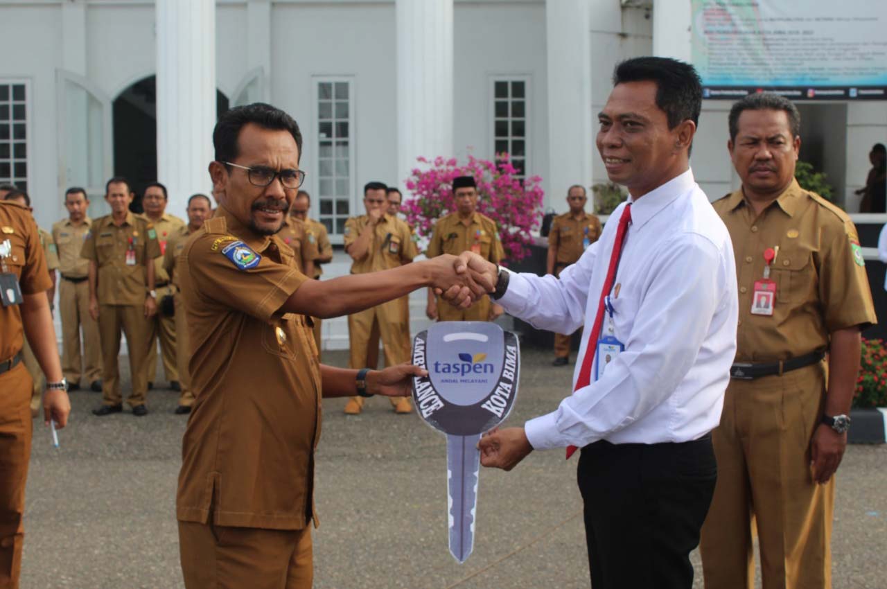 BANTU PELAYANAN: Kepala PT Taspen (Persero) Cabang Mataram Tribuna Phitera Djaja (dua dari kanan) serahkan kunci mobil ambulance secara simbolis kepada Walikota Bima H Muhammad Lutfi (kiri) di halaman kantor Walikota Bima, Senin (2/3).
