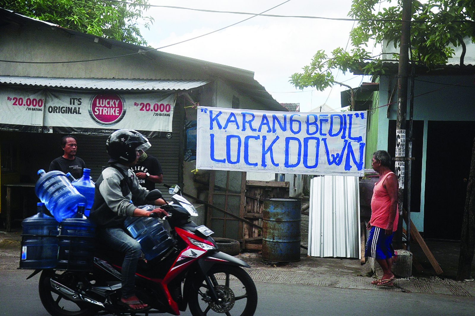 SATU PINTU: Kepala Lingkungan Karang Bedil Mirwandi Fiqri (pakai topi) menutup enam pintu masuk di Lingkungan Karang Bedil, kemarin (30/3).