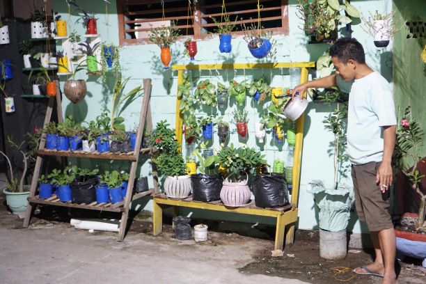 MENYIRAM BUNGA: Warga Lingkungan Bermi, Kelurahan Pancor, Kecamatan Selong sedang menyiram bunga di gang kampungnya, Minggu (12/4). (Ayep for Lombok Post)