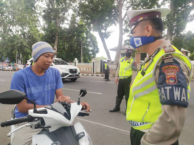 TEGURAN: Satlantas Polresta Mataram menegur salah seorang pengendara saat melintas di Jalan Langko karena tidak mengenakan helm dan masker beberapa waktu lalu. (Harli/Lombok Post)