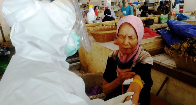UJI CEPAT: Salah seorang pedagang Pasar Mandalika menahan nyeri saat tim medis mengambil sampel darahnya, Senin (11/5/20)  lalu. (Sirtu/Lombok Post)