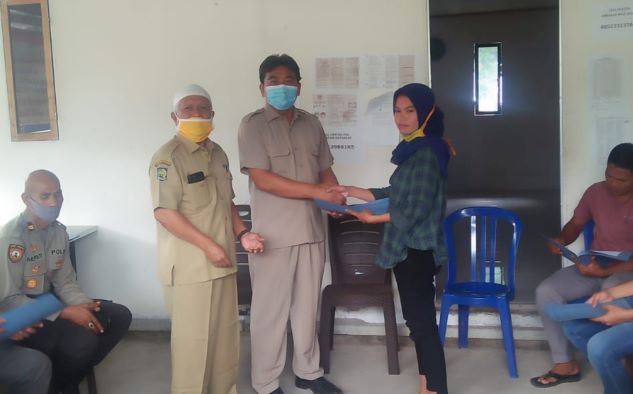 SERAHKAN SK: Dari kiri; Kepala DP2KBPMD KLU H Kholidi Halil dan Asisten I Setda KLU Kawit Sasmita menyerahkan SK pengangkatan kembali pada salah satu perangkat yang diberhentikan kades Sesait, di Kantor Desa, Selasa (23/6). (DP2KBPMD for Lombok Post)