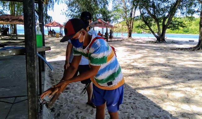 TERAPKAN PROTOKOLER KESEHATAN: Seorang wisatawan diwajibkan mengenakan masker dan mencuci tangan dengan sabun saat baru tiba di Gili Nanggu, Desa Sekotong Barat, Rabu (24/6).( TONI/LOMBOK POST)