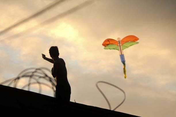 SUDAH DILARANG: Seorang pria bermain layangan di atap sebuah bangunan di Lingkungan Karang Tapen, Kelurahan Cilinaya, Rabu (17/6).( IVAN/LOMBOK POST)