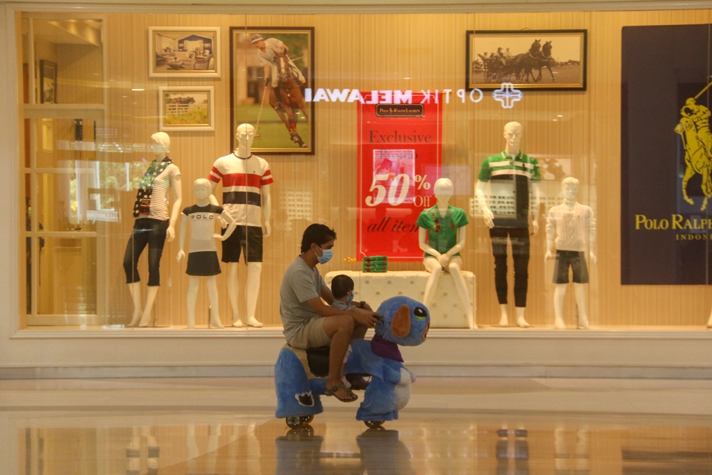TETAP IKUTI PROTOKOL: Seorang pria menemani anaknya bermain di Lombok Epicentrum Mall, Kota Mataram, belum lama ini. Warga akhirnya bisa berlibur setelah sekian lama diam di rumah saja.