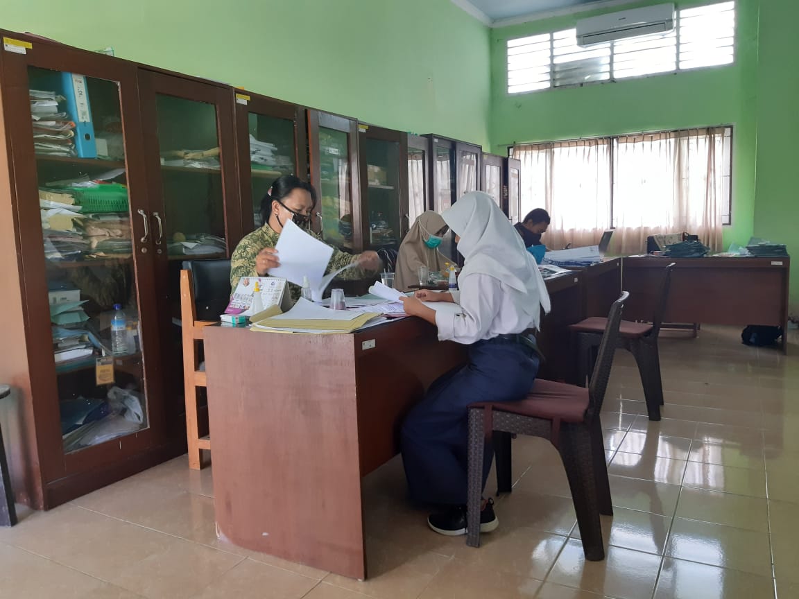 SERIUS: Ketua Panitia PPDB SMKN 7 Mataram Putu Supartini memverfikasi berkas fisik seorang calon siswa baru, kemarin (30/6/2020).