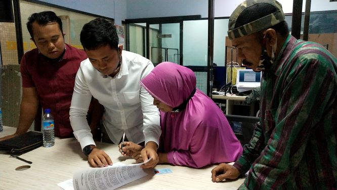 BELUM TERIMA MAAF: Ibu Mahsun (berhijab) menandatangani berita acara pemeriksaan didampingi penasihat hukumnya Anton Hariono di ruang Subdit V bidang Cyber Crime Ditreskrimsus Polda NTB, Jumat (3/7).( HARLI/LOMBOK POST)