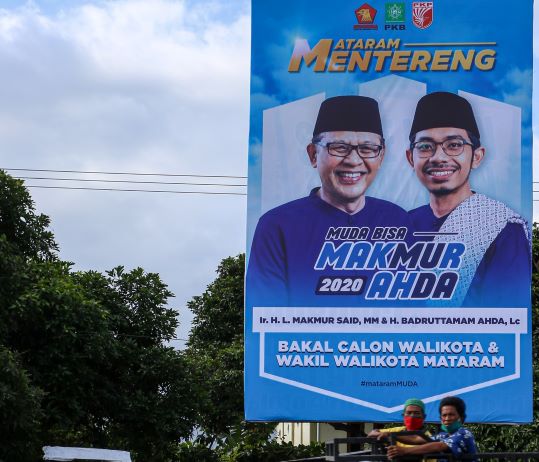 MULAI PASANG BALIHO: Baliho pasangan HL Makmur Said dan H Badruttamam Ahda mulai terpasang di sejumlah ruas jalan Kota Mataram. Salah satunya di Jalan Bung Hatta pertigaan ke arah Sayang-Sayang. (IVAN/LOMBOK POST)