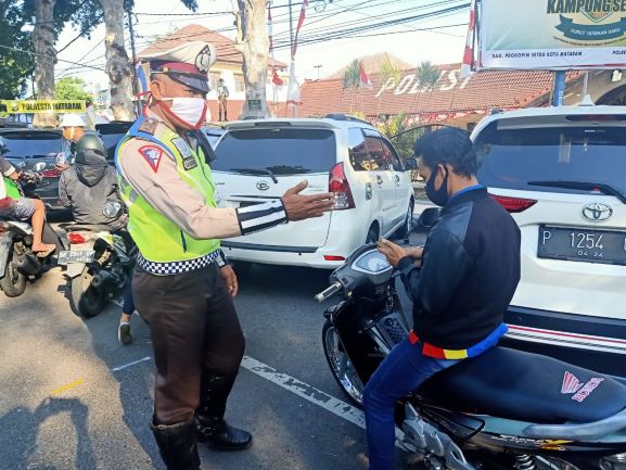 JANGAN DITIRU: Seorang pengendara tak menggunakan helm ditilang polisi saat melintas di Jalan Langko, Mataram,  Jumat (24/7).( HARLI/LOMBOK POST)