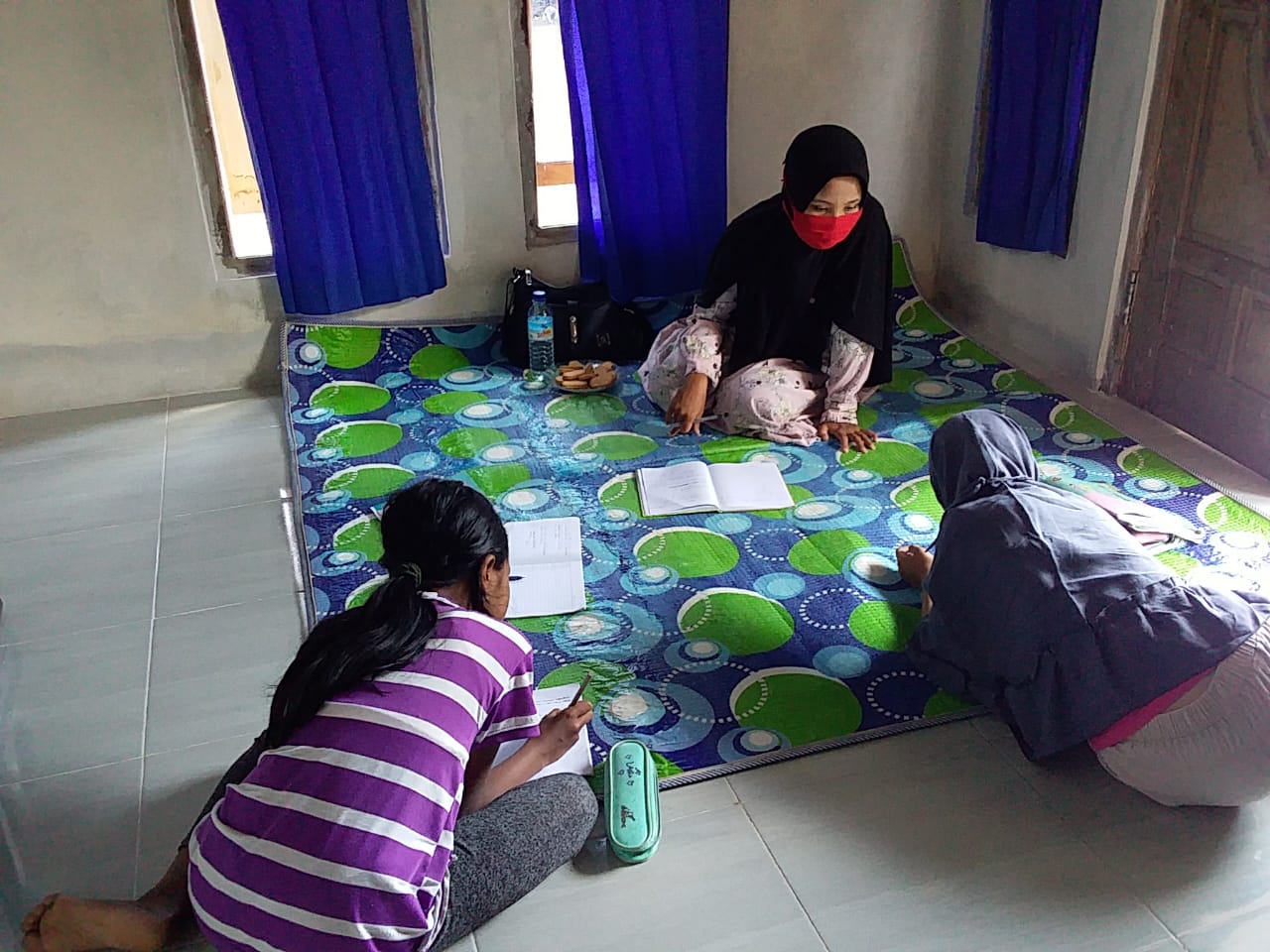 TUGAS MULIA: Seorang guru SDN 30 Cakranegara menunggui murid-muridnya mengerjakan tugas, saat melakukan kunjungan rumah, beberapa waktu lalu.