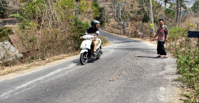 RETAK-RETAK: Salah seorang warga menunjukkan retak dan berlubang di jalan Keling-Jabon Desa Selong Belanak, Praya Barat, belum lama ini. (Dedi/Lombok Post)