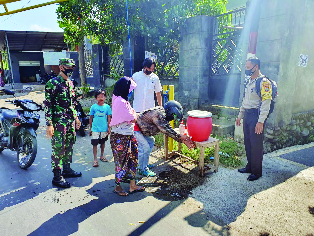 WARGA WAJIB PATUH: Sejumlah warga yang hendak masuk ke Desa Kebon Ayu diwajibkan menggunakan masker dan cuci tangan.( TONI/LOMBOK POST)