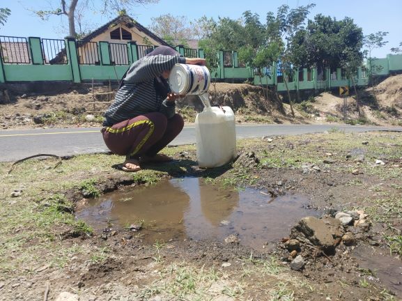 KEKERINGAN: Seorang warga mengambil air rembesan dari pipa PDAM yang bocor, di Desa Sambik Elen, Bayan, beberapa waktu lalu. (Dok/Lombok Post)