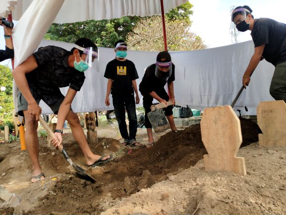 MEMECAHKAN MISTERI GANTUNG DIRI: Petugas menggali kubur LNS untuk proses otopsi di pemakaman umum Karang Medain Mataram, Senin  (3/8).( HARLI/LOMBOK POST)