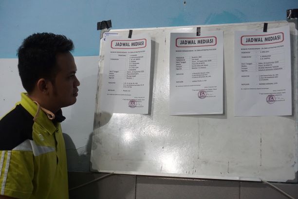 MELIHAT JADWAL: Koordinator Administrasi Bale Mediasi Lotim Lalu Dhodik Martha Sumarna sedang mengecek jadwal mediasi di kantor Bale Mediasi Lotim, kemarin (18/9). (Fatih/Lombok Post)