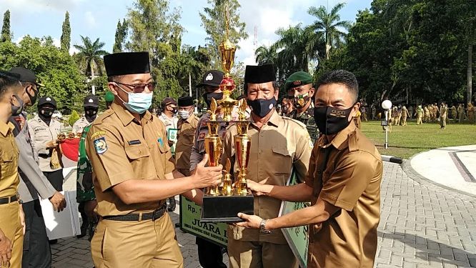 MENERIMA HADIAH: Kepala Desa Pesanggrahan H Badrun menerima menerima piala juara II lomba Kampung Sehat tingkat kabupaten dari Sekda Lotim HM Juaini Taofik. (FATIH/LOMBOK POST)