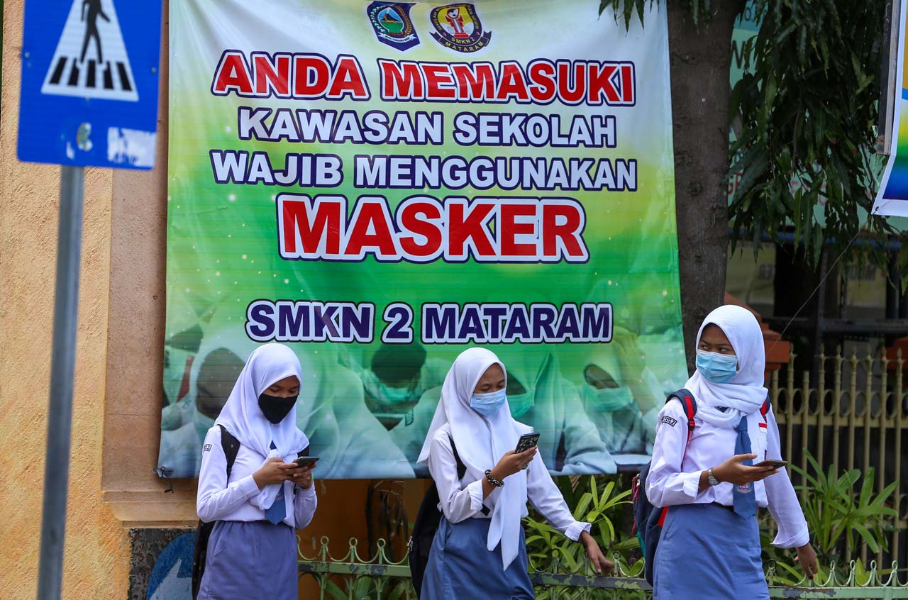 MASIH DIKAJI: Tiga orang siswa SMKN 2 Mataram menunggu jemputan di Jalan Pemuda, Gomong, Kota Mataram, belum lama ini. Masuk sekolah di Kota Mataram tunggu izin dari Pemkot Mataram.